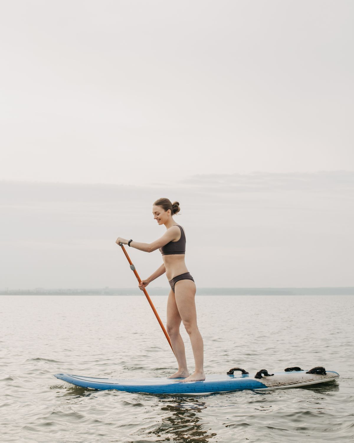 Woman paddle boarding on a calm lake in summer