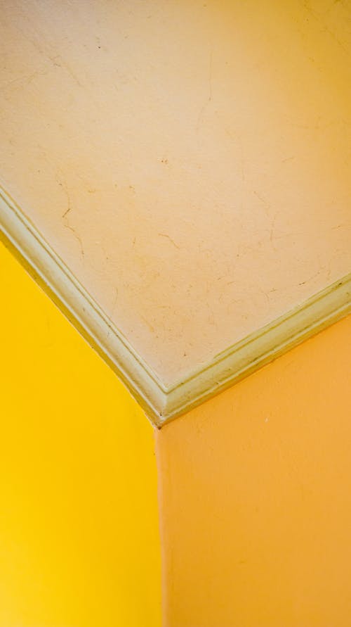 Low angle of vivid yellow walls and ceiling with scratches and spots on surface