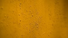 Uneven yellow wall with irregular grains