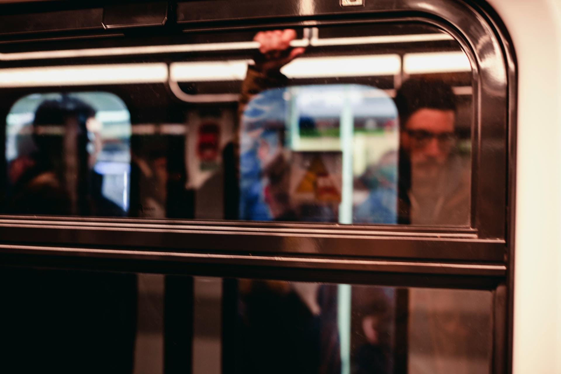 Blurred reflections of commuters on a moving train in Milano, Italy.