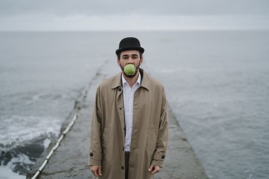 Man in Beige Coat holding Green Apple 