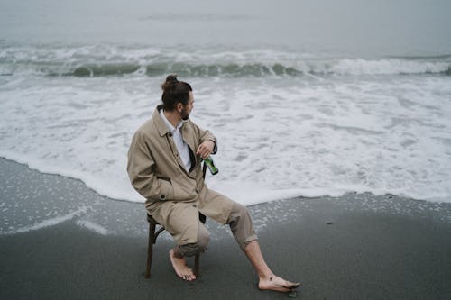 Free  Man Sitting on Stool at the Seashore
 Stock Photo