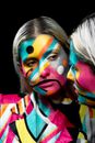 Crop young woman with bright geometric makeup on face reflecting in mirror on black background