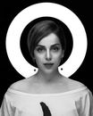 Black and white of stylish woman with makeup and cactus looking at camera against ring lamp