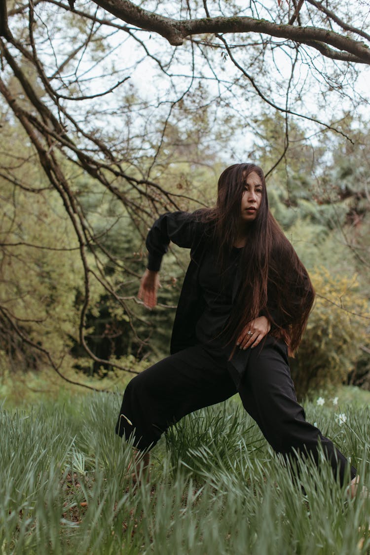 Woman In Black Clothes Exercising On Green Grass