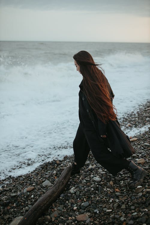 A Woman Walking on a Rocky Shore