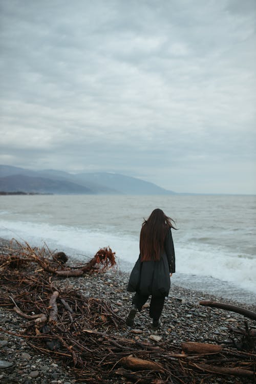 
A Woman Walking on a Rocky Shore