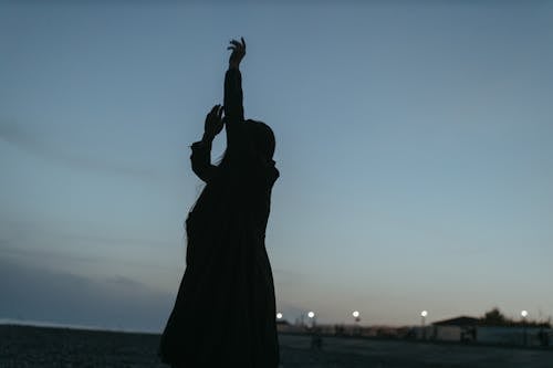 Silhouette of Woman Raising Her Hands 
