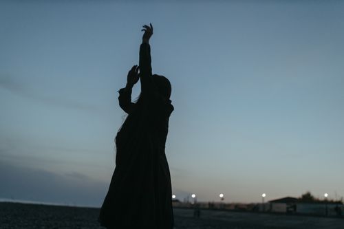 Free A silhouette of a woman with hands raised against a dusky sky, evoking tranquility and freedom. Stock Photo