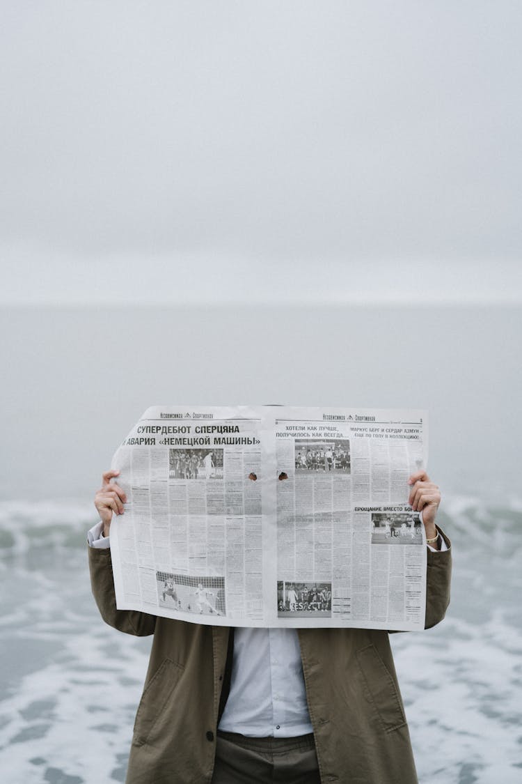 A Person Reading Newspaper At The Beach