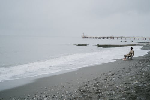 A Man Sitting on Chair at the Seashore