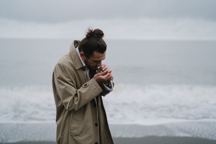 Man Lighting A Cigarette With A Match On Beach