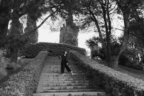 Grayscale Photo of a Woman Standing on Stairs