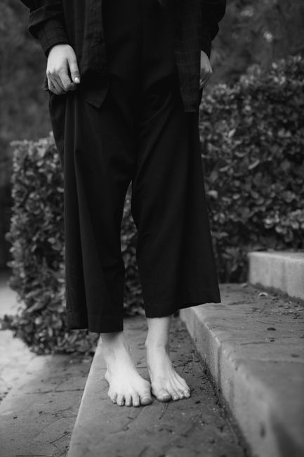 Artistic monochrome photo of a person standing barefoot on stairs outdoors.