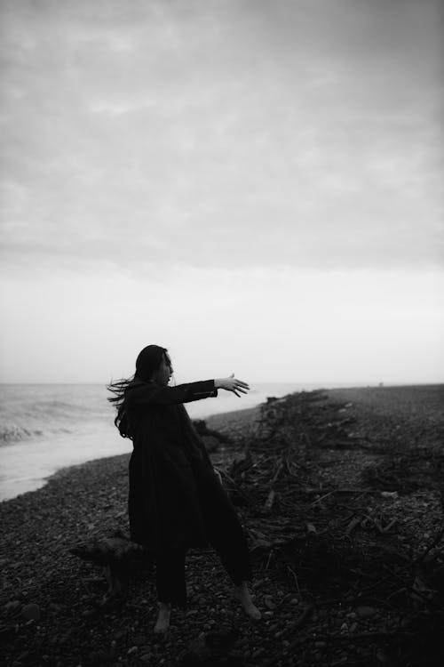 Free Grayscale Photo of a Woman Dancing on Shore Stock Photo