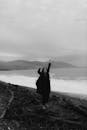 A Grayscale of a Woman Wearing a Black Outfit on a Shore