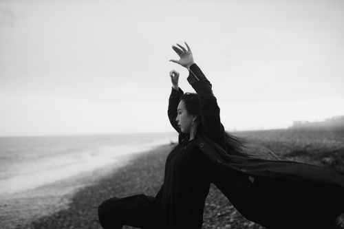 Free Artistic black and white portrait of a woman dancing by a windy coast, capturing movement. Stock Photo