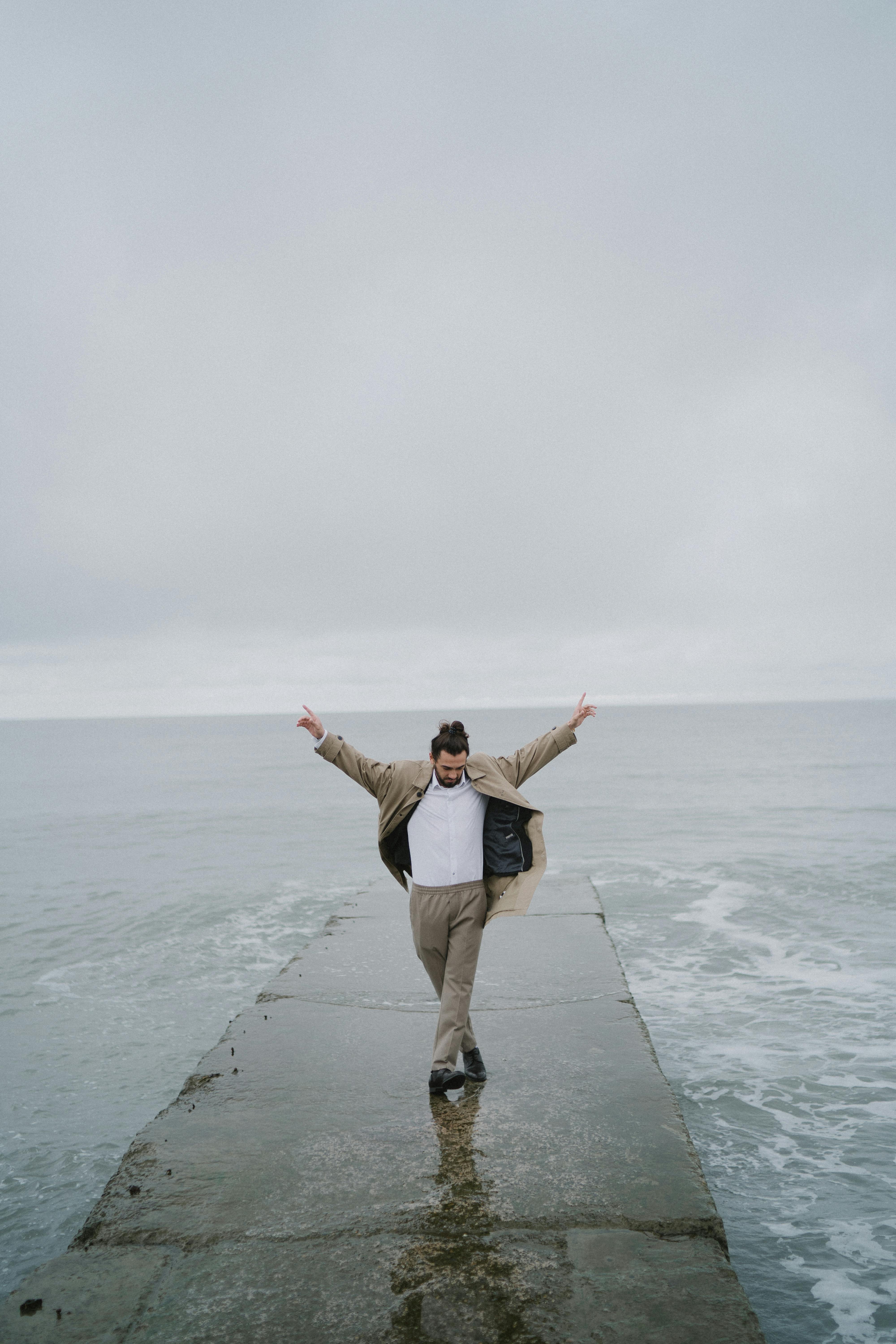 A Man in Beige Jacket Standing on Concrete Dock · Free Stock Photo