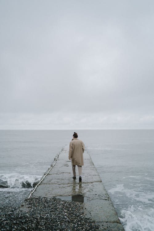 A Person Walking on a Concrete Pier