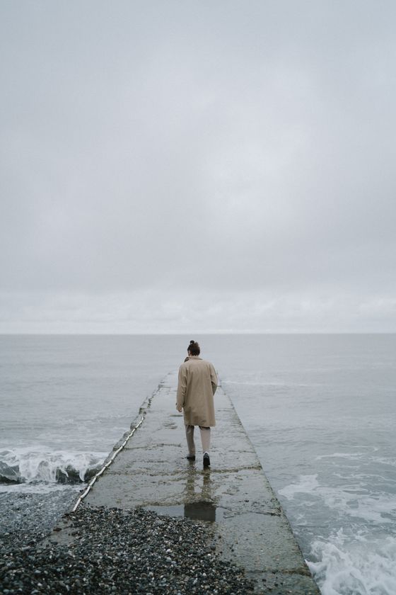 Figure in a long coat standing at the water's edge, photo by Anastasia Shuraeva on Pexels
