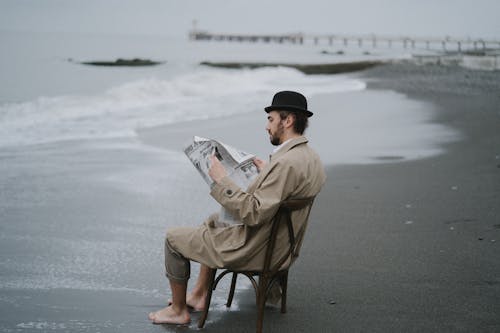 Free A Man Reading a Newspaper on a Beach Stock Photo