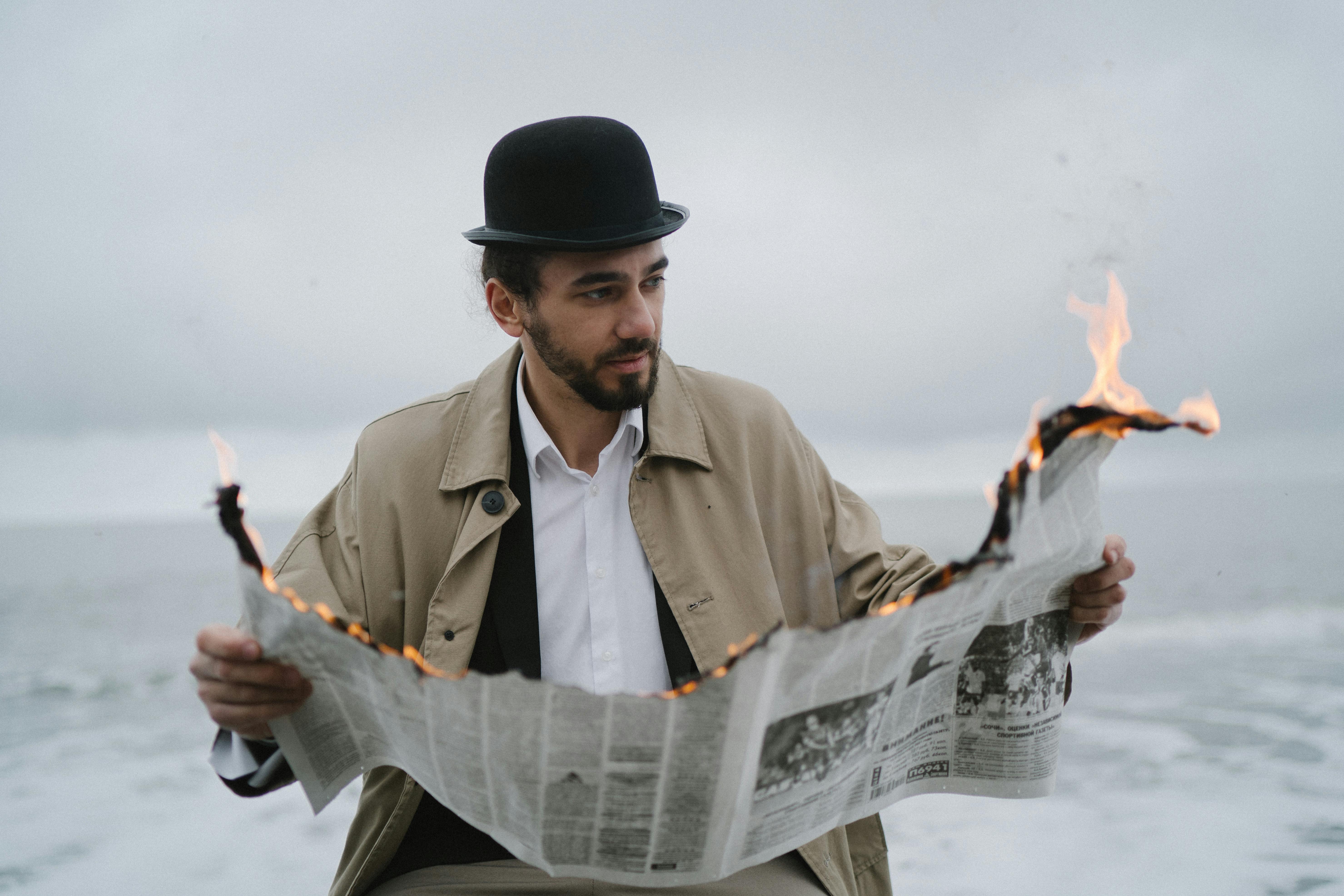 a bearded man reading a burning newspaper