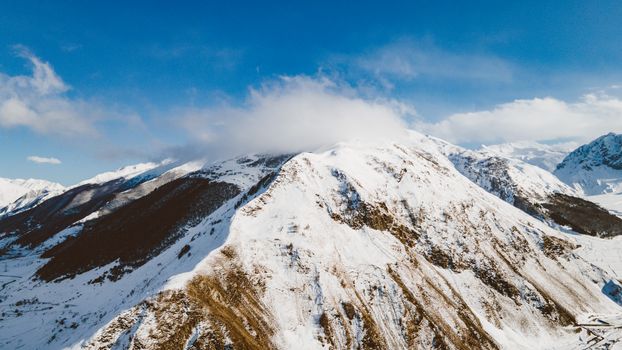 Stunning aerial view of a majestic snow-covered mountain range under a clear blue sky.