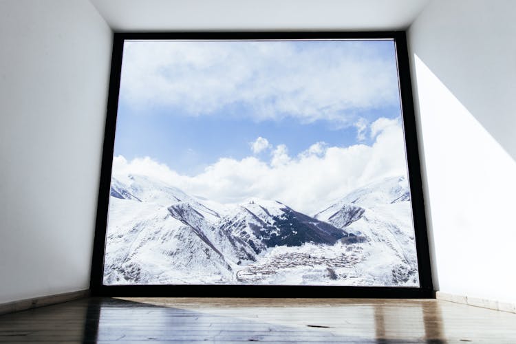 A Window Overlooking A Snow Covered Mountains