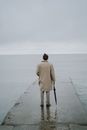 Woman in Brown Coat Walking on the Beach