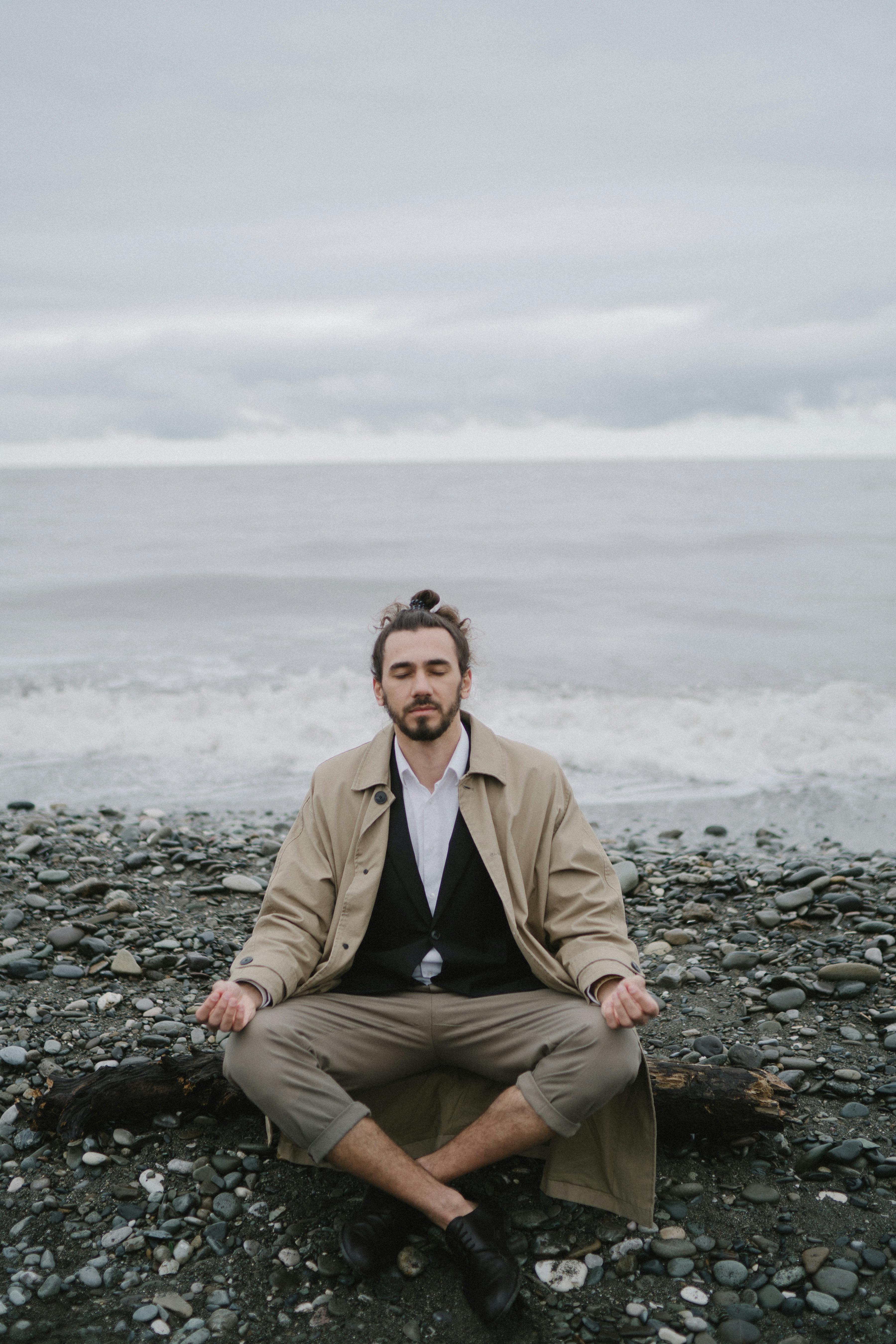 一个男人坐在海边的岩石海滩上冥想的宁静时刻