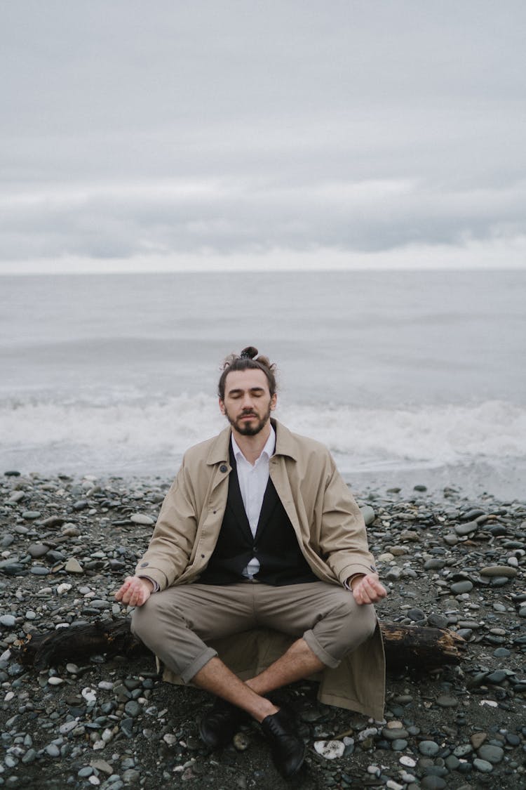 A Man Sitting On The Beach While Meditating