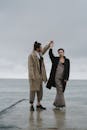 一对优雅的夫妇穿着风衣在海边的码头上跳舞，散发着浪漫和风格