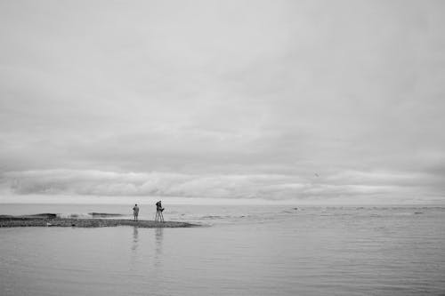 A Grayscale Photo of People Standing on the Beach