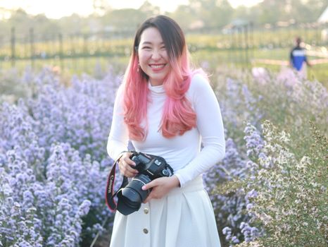 A Woman in White Sweater Holding a Camera Standing on a Flower Field
