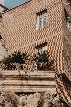 Rustic brick building with tropical plants in a low-angle shot.