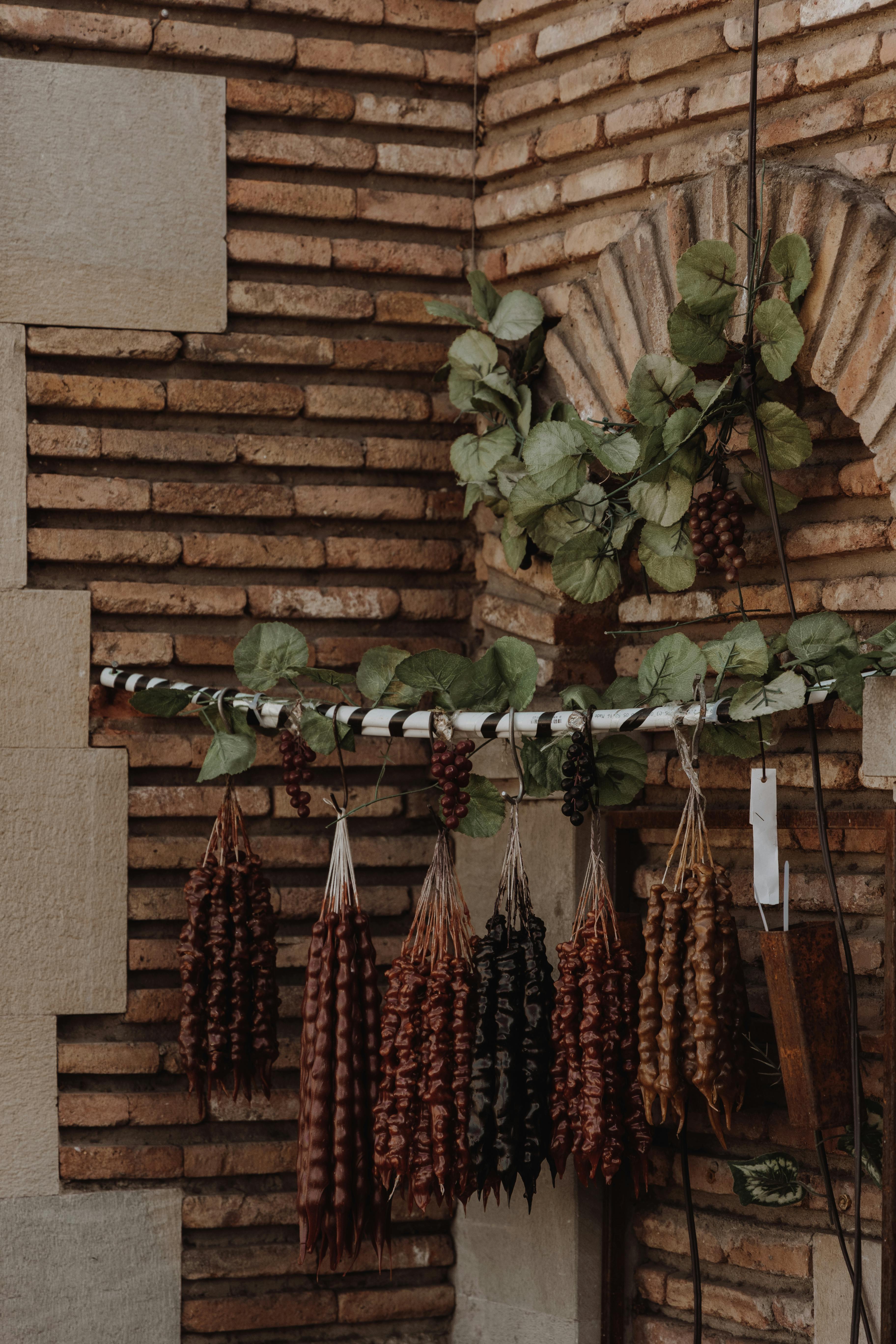 Warm rustic scene of hanging dried fruits and leaves on a brick wall, evoking vintage charm.