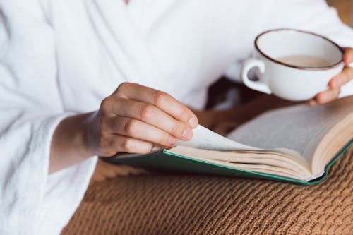Free Person Hand on a Book while Drinking Coffee Stock Photo