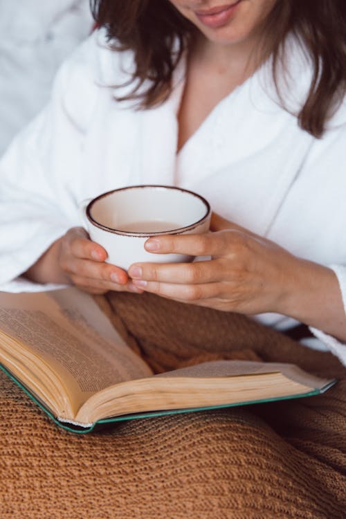 Free A Person Holding a Drink While Reading  Stock Photo
