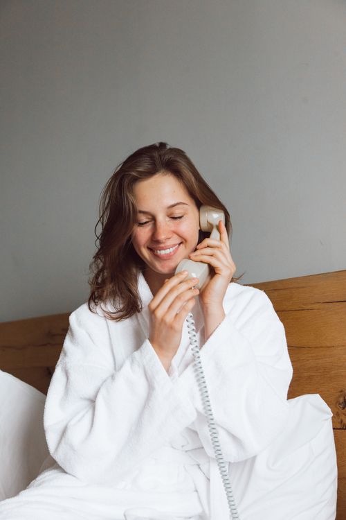 Free Relaxing woman in a bathrobe smiling and talking on a telephone indoors. Stock Photo