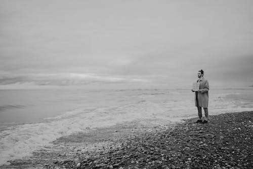 Grayscale Photo of Man Standing on Shore