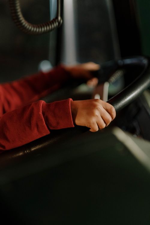 Free Close view of hands gripping steering wheel inside a vehicle with red sleeves. Stock Photo
