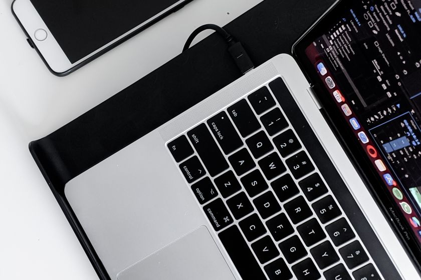An iPhone beside a MacBook on a white desk