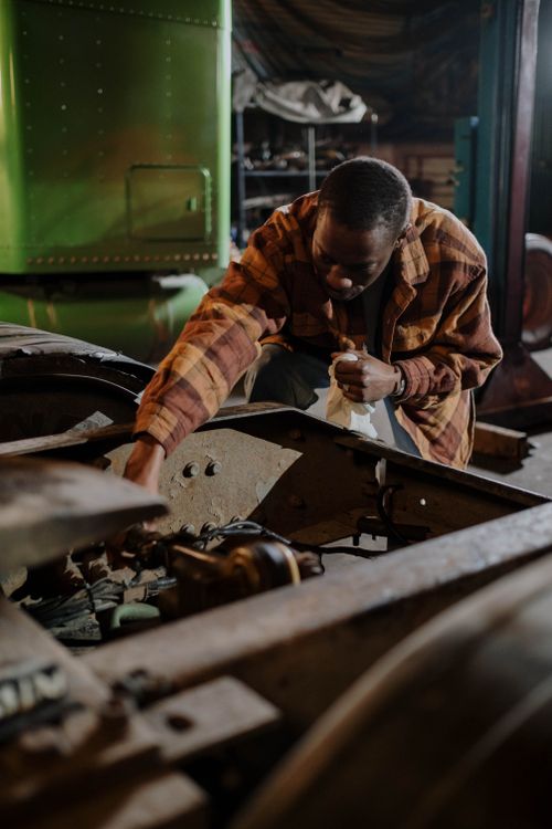 Free African American mechanic intensely repairing a truck in an indoor garage setting. Stock Photo