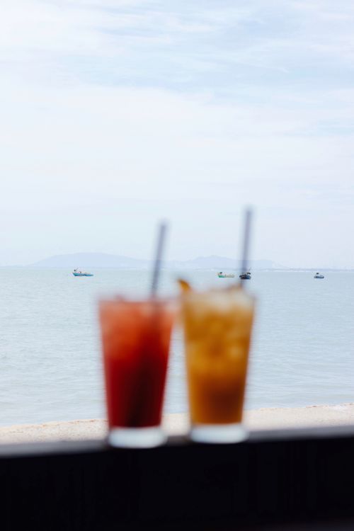 Free Refreshing cocktails on a beach with a serene ocean view in the background. Stock Photo