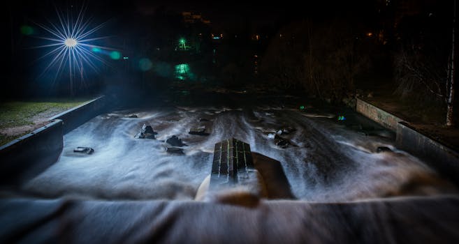 A long exposure shot of a vibrant river at night with striking light reflections and misty water flow.