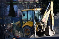 Yellow and Black Backhoe Near the Wire Fence