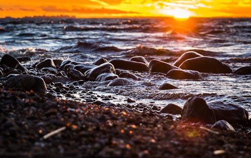 Stones Surrounded by Body of Water during Sunset