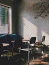 Corner of modern cozy cafe with sofa placed near window and chairs at tables
