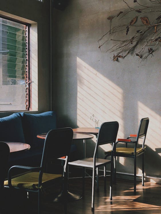 Free Corner of modern cozy cafe with sofa placed near window and chairs at tables Stock Photo