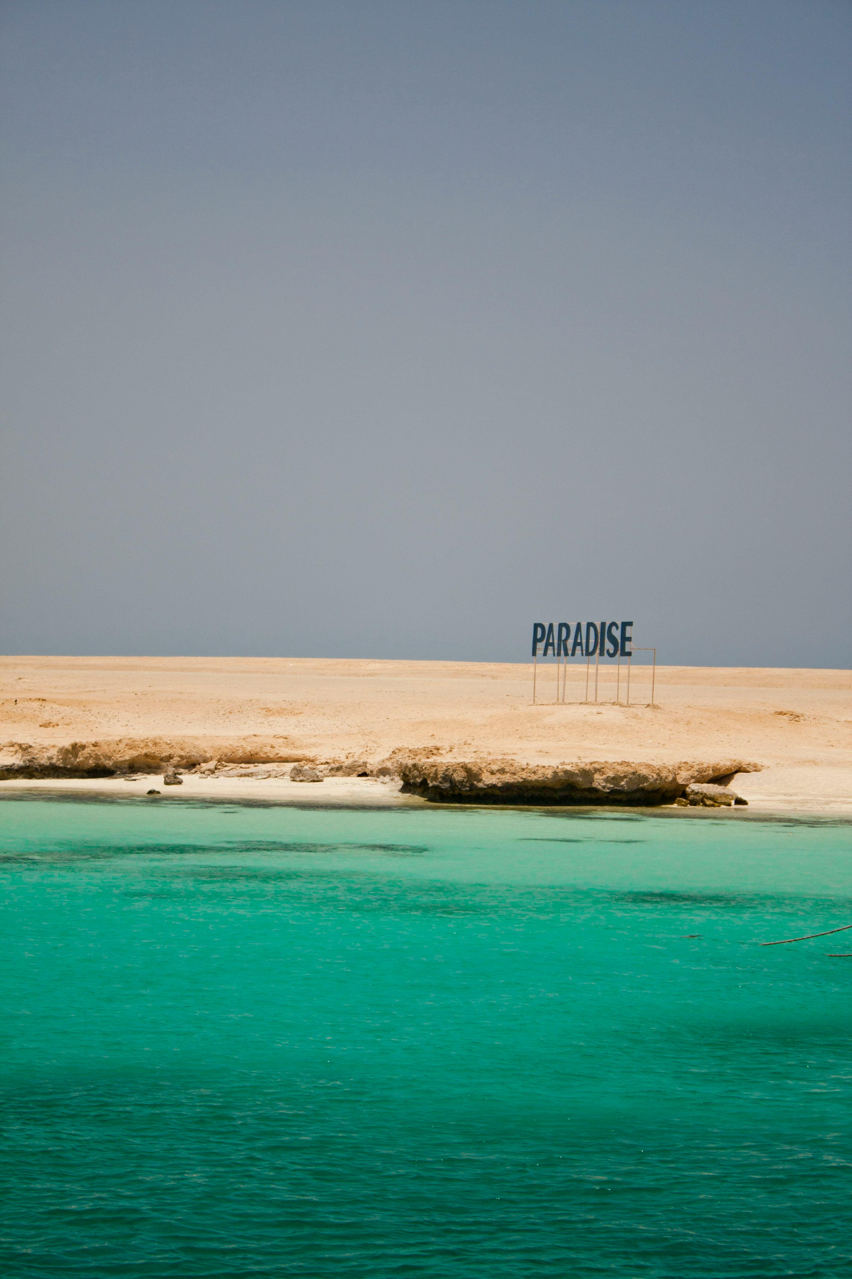 A tranquil beach scene featuring turquoise waters and a 'Paradise' sign in Red Sea Governorate.